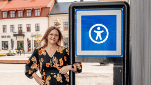 En bild på en UX-designer som vid sidan av en skylt med en tillgänglighetssymbol